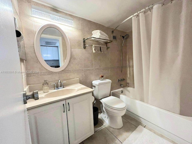 full bathroom with tile patterned floors, toilet, shower / tub combo with curtain, vanity, and tile walls