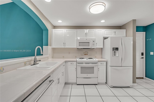 kitchen with white cabinets, white appliances, sink, and light tile patterned floors