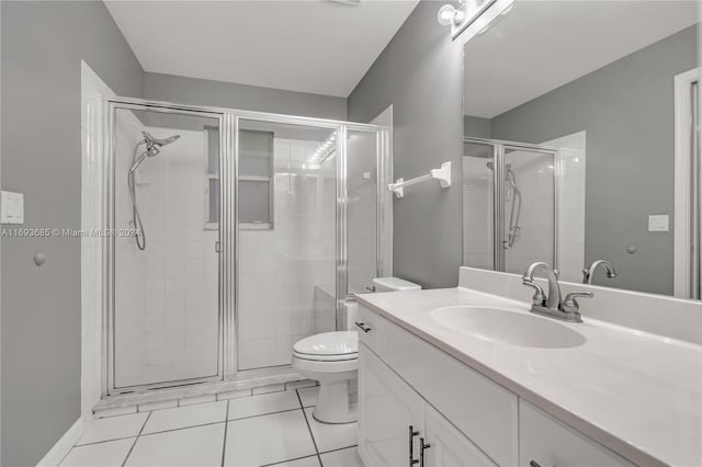 bathroom featuring tile patterned flooring, vanity, toilet, and a shower with door