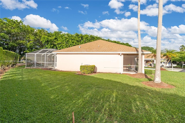 view of side of property with a lawn and glass enclosure