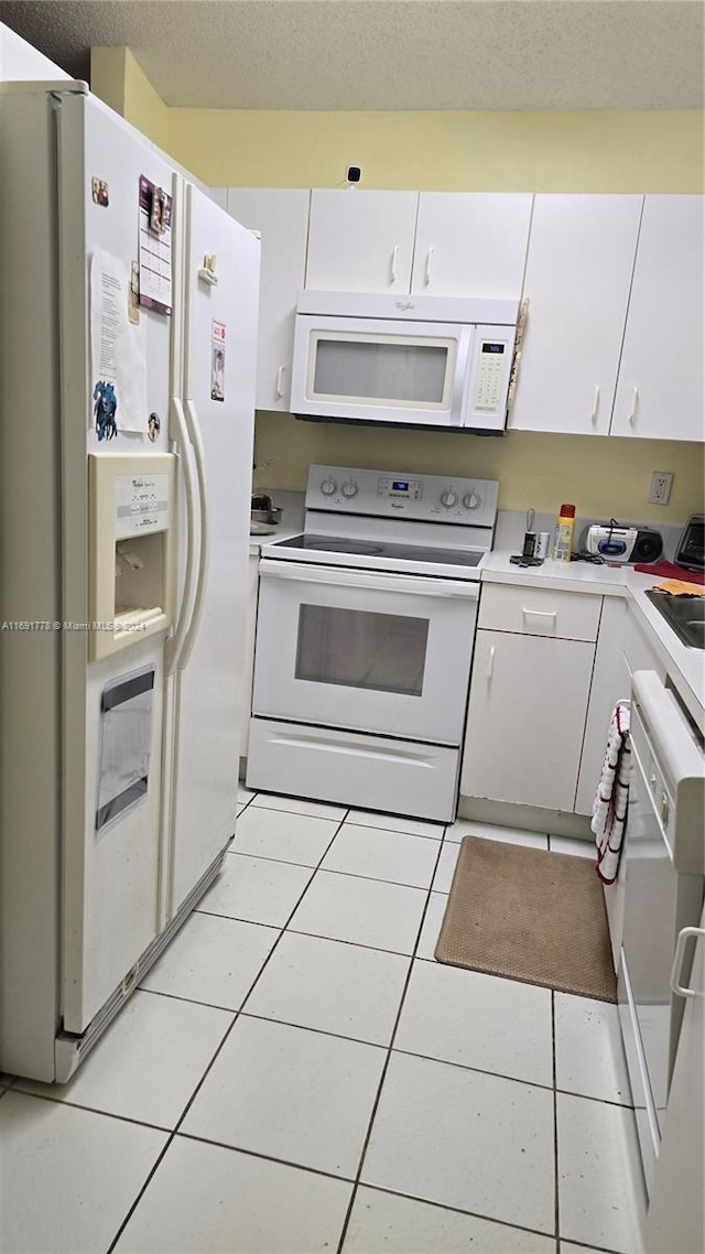 kitchen featuring white cabinets, a textured ceiling, white appliances, and light tile patterned flooring