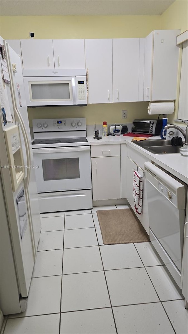 kitchen with white cabinets, light tile patterned floors, white appliances, and sink