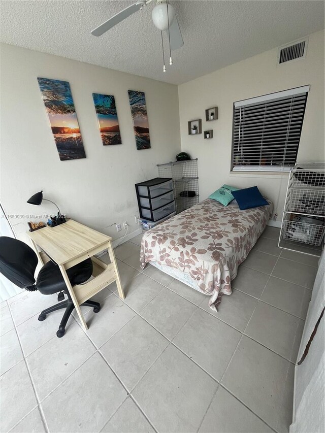 bedroom with a textured ceiling, tile patterned floors, and ceiling fan