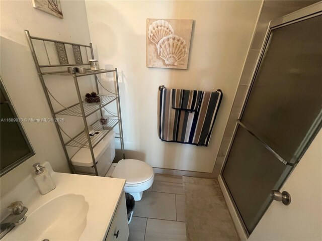 bathroom featuring tile patterned flooring, toilet, vanity, and walk in shower