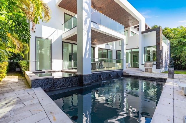 rear view of house with pool water feature, an outdoor kitchen, and a patio area