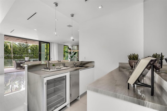 kitchen with white cabinetry, sink, beverage cooler, and decorative light fixtures