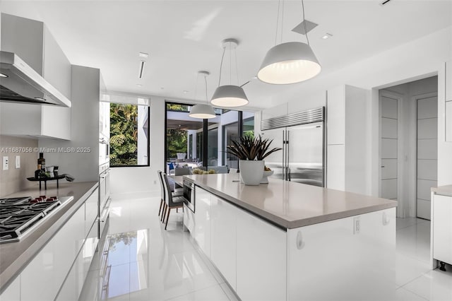 kitchen with decorative light fixtures, stainless steel appliances, a center island, and white cabinets