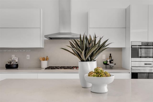 details with white cabinetry, appliances with stainless steel finishes, and wall chimney exhaust hood