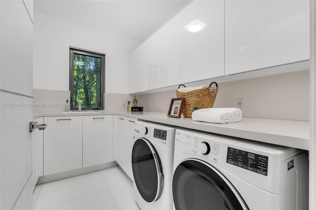 clothes washing area with light tile patterned floors, washing machine and dryer, and cabinets