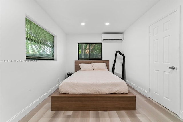 bedroom with a wall mounted air conditioner and light wood-type flooring