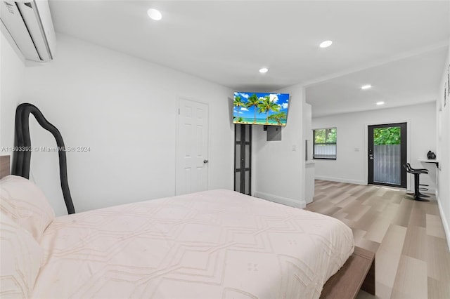 bedroom featuring an AC wall unit, access to outside, and light wood-type flooring