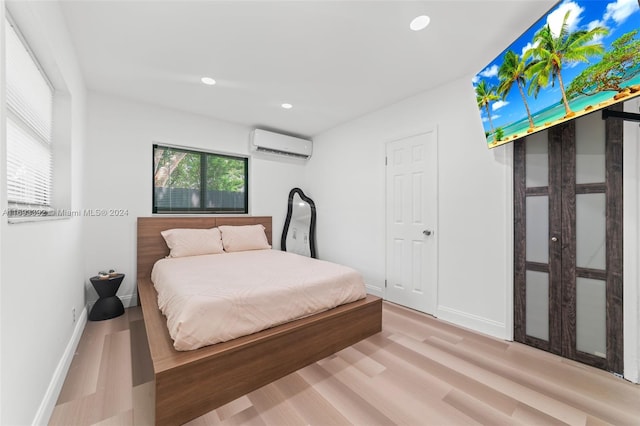 bedroom with a wall unit AC and light hardwood / wood-style flooring