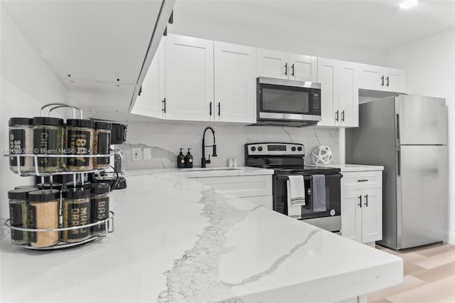 kitchen with white cabinetry, sink, stainless steel appliances, and light stone counters