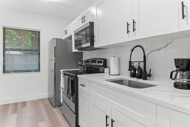 kitchen with light stone countertops, decorative backsplash, stainless steel appliances, sink, and white cabinetry