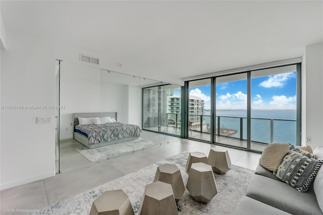 bedroom featuring access to outside, floor to ceiling windows, and a water view