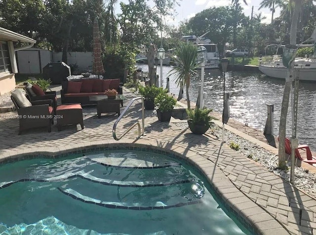 view of swimming pool with outdoor lounge area, a patio area, a water view, and a storage shed