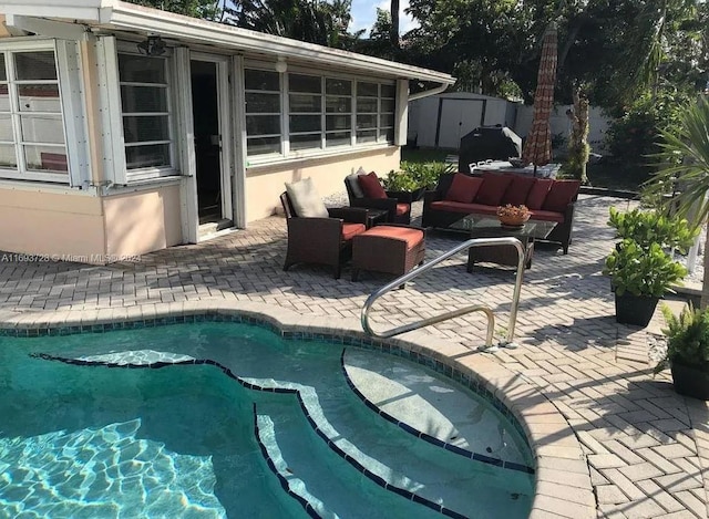 view of swimming pool with outdoor lounge area, a storage shed, and a patio