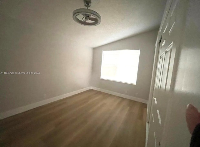 unfurnished room with hardwood / wood-style floors and vaulted ceiling