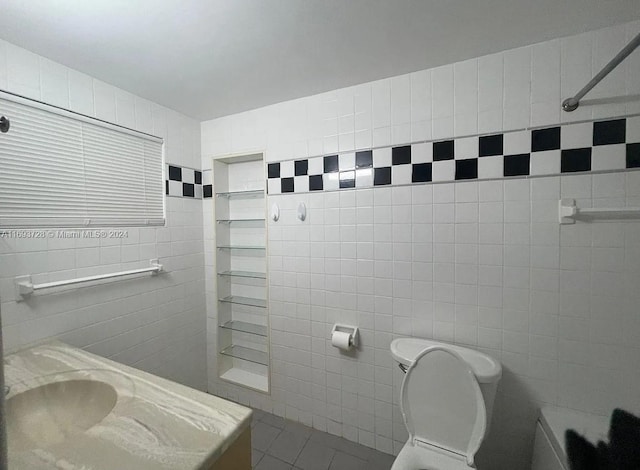 bathroom featuring toilet, tile patterned floors, and tile walls