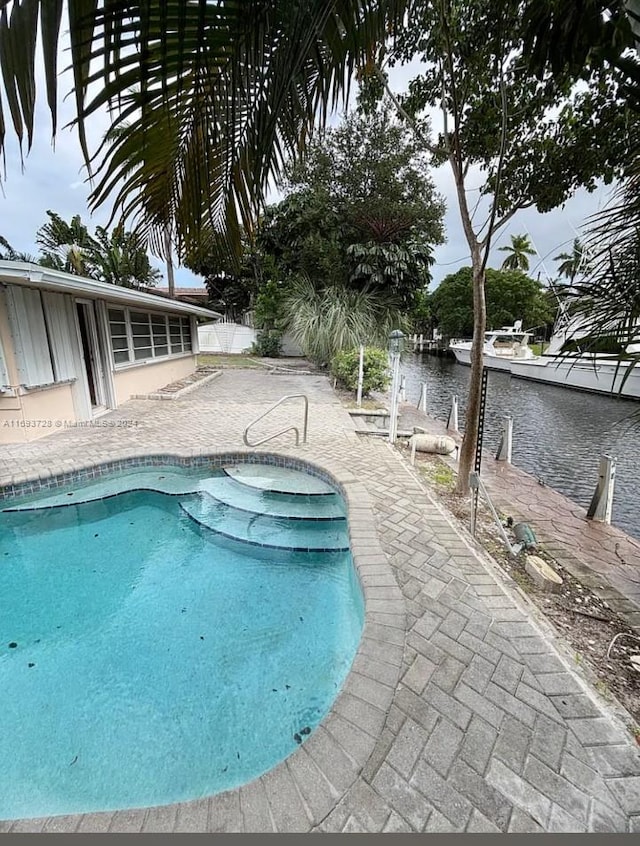 view of pool with a water view and a patio