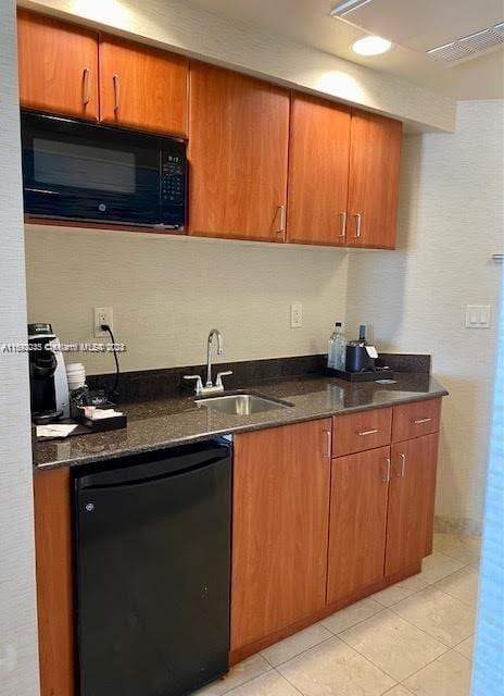 kitchen with black appliances, light tile patterned flooring, dark stone countertops, and sink