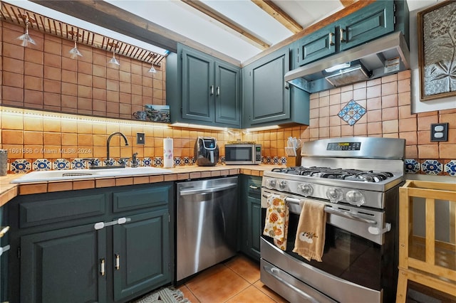 kitchen featuring tile countertops, appliances with stainless steel finishes, light tile patterned floors, and tasteful backsplash