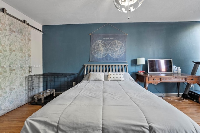 bedroom featuring a barn door and hardwood / wood-style flooring