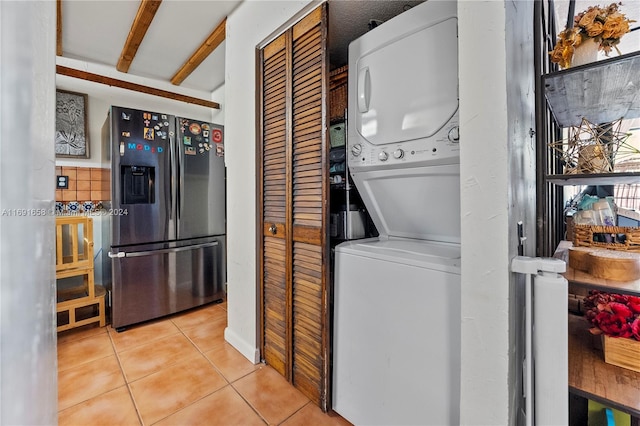 laundry room featuring stacked washing maching and dryer and light tile patterned floors