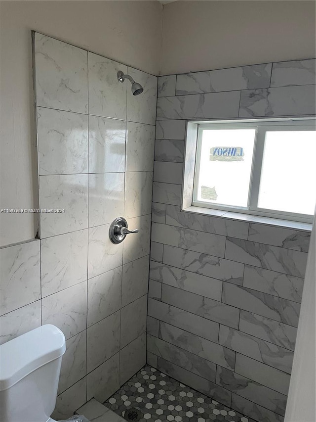 bathroom with a tile shower and toilet