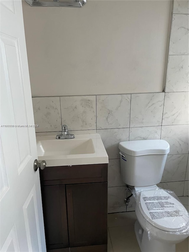 bathroom with vanity, toilet, and tile walls