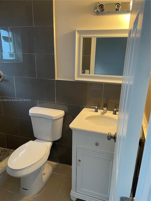 bathroom with toilet, tile patterned floors, and tile walls