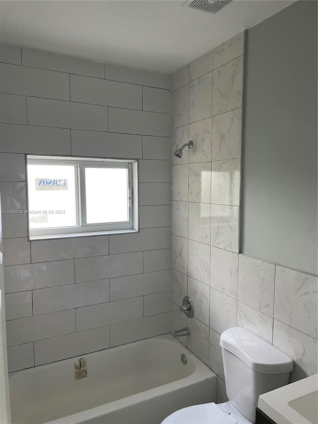 full bathroom featuring vanity, toilet, tile walls, and tiled shower / bath combo