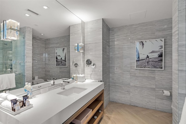 bathroom featuring parquet flooring, vanity, tile walls, and a shower with shower door