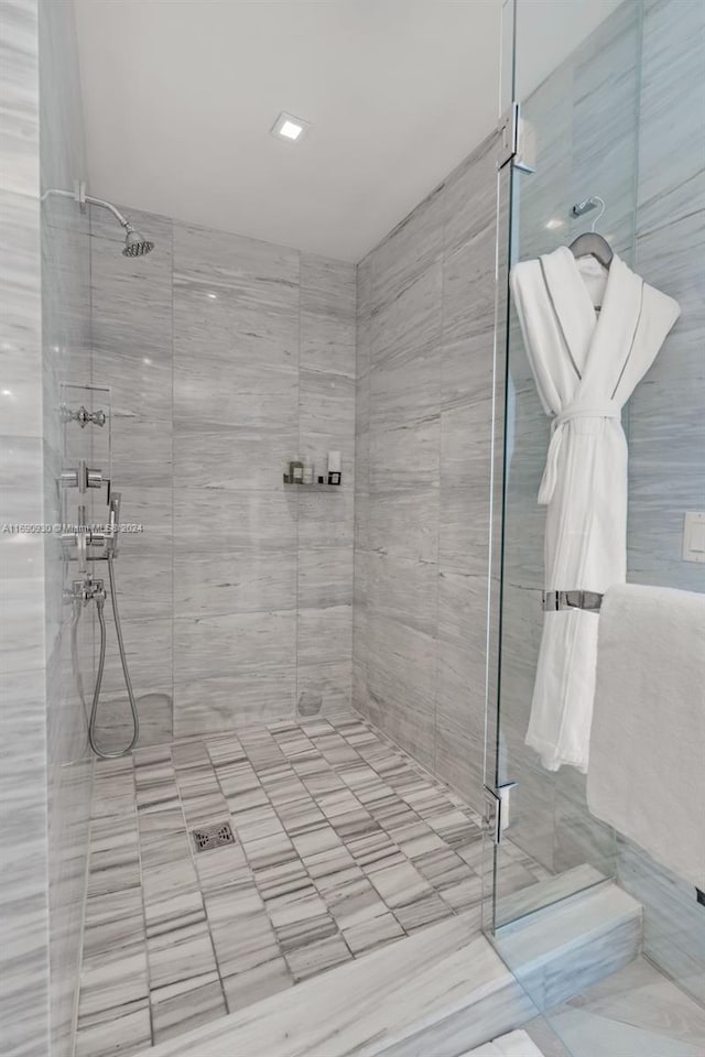 bathroom with a tile shower and tile walls