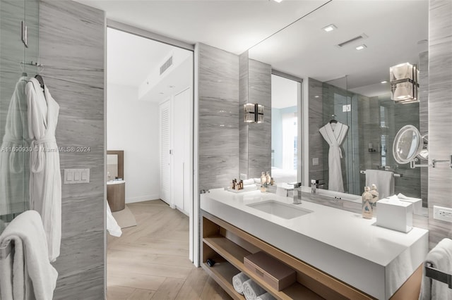 bathroom with vanity, an enclosed shower, parquet floors, and tile walls