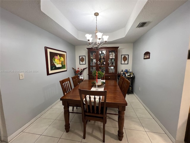 tiled dining space featuring a textured ceiling, a tray ceiling, and a notable chandelier