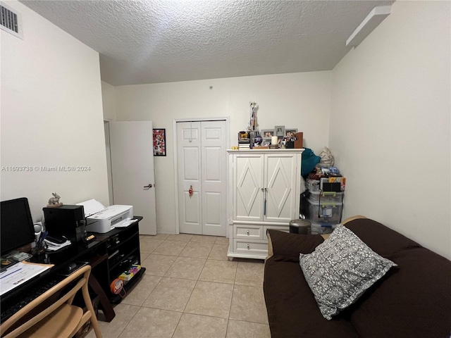 interior space featuring light tile patterned floors, a textured ceiling, and a closet