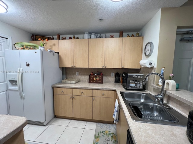 kitchen with a textured ceiling, white refrigerator with ice dispenser, sink, and light tile patterned floors