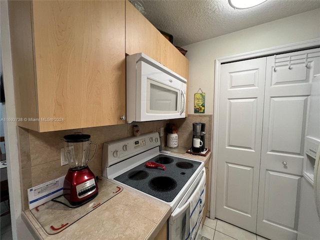 kitchen featuring backsplash, tile countertops, a textured ceiling, white appliances, and light tile patterned floors