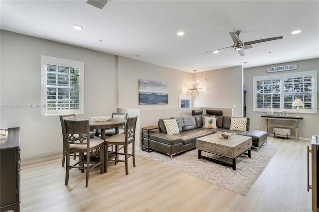 living room with light hardwood / wood-style floors and ceiling fan with notable chandelier