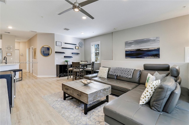 living room featuring ceiling fan, light hardwood / wood-style flooring, and sink