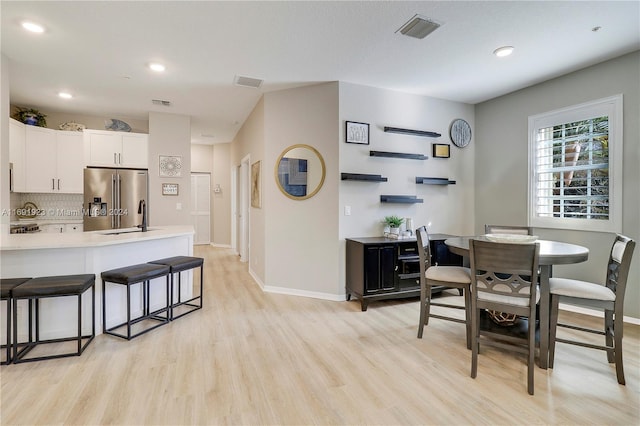 dining space with light wood-type flooring and sink