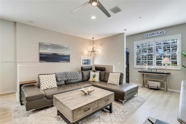 living room with ceiling fan with notable chandelier and light hardwood / wood-style floors