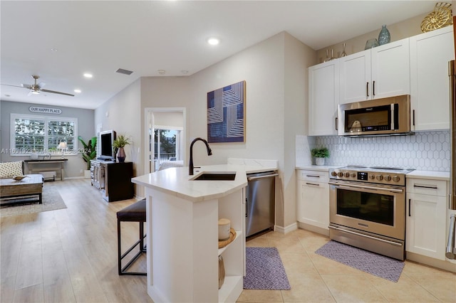 kitchen featuring light hardwood / wood-style floors, white cabinetry, kitchen peninsula, and stainless steel appliances