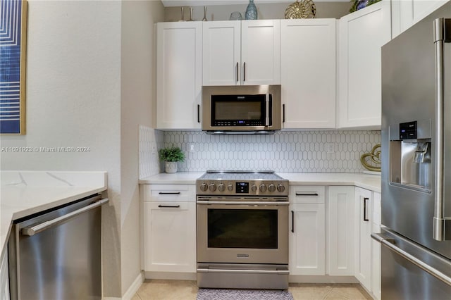 kitchen featuring tasteful backsplash, light tile patterned flooring, light stone counters, white cabinetry, and stainless steel appliances