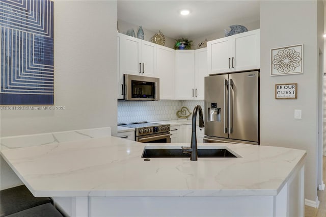 kitchen with backsplash, sink, light stone counters, white cabinetry, and stainless steel appliances