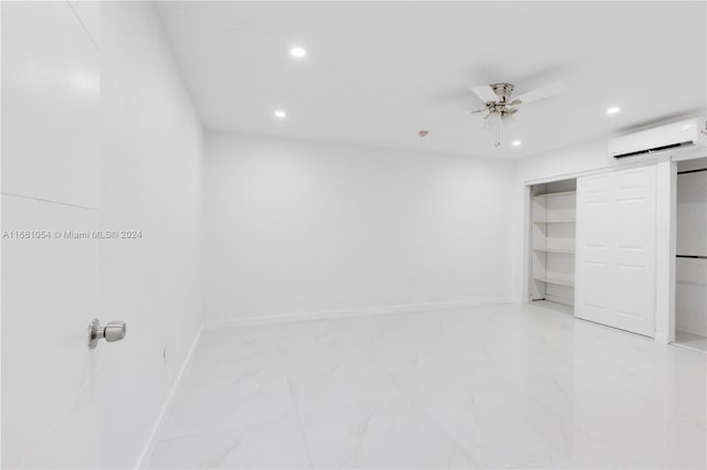 unfurnished bedroom featuring a barn door, a closet, a wall unit AC, and ceiling fan