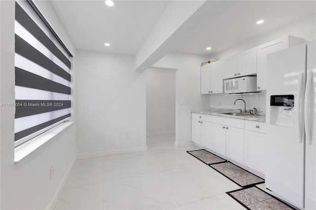 kitchen with white appliances, white cabinetry, and sink