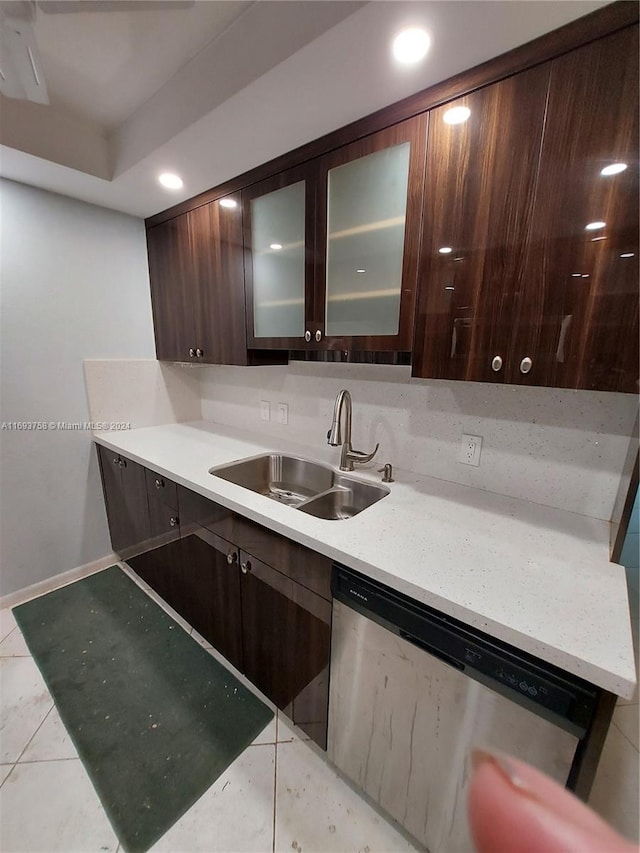 kitchen with dark brown cabinets, dishwasher, sink, and light tile patterned flooring