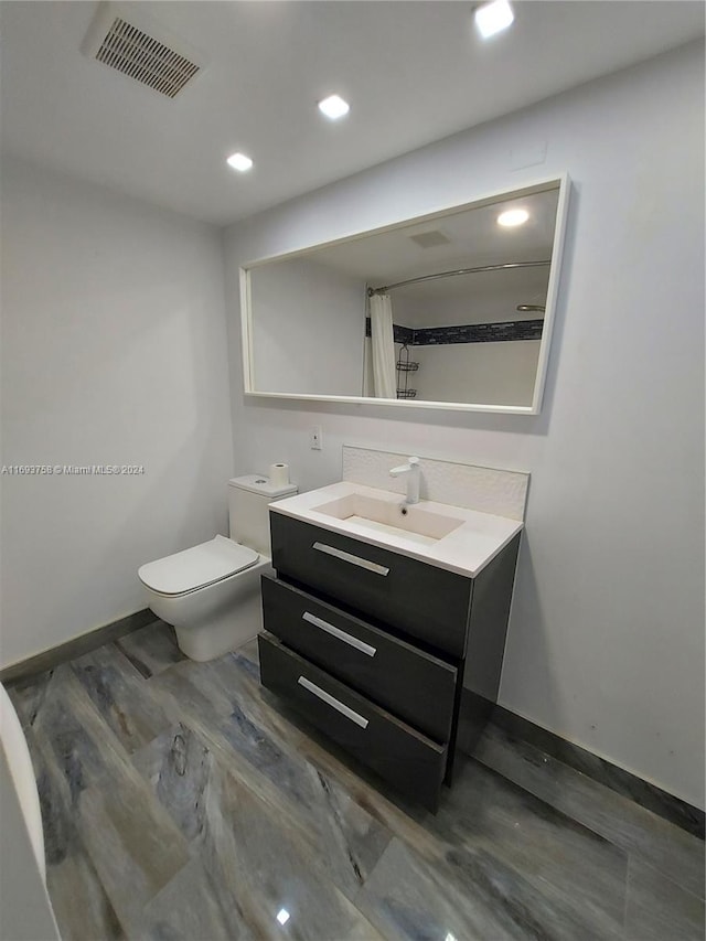 bathroom featuring vanity, hardwood / wood-style flooring, toilet, and curtained shower